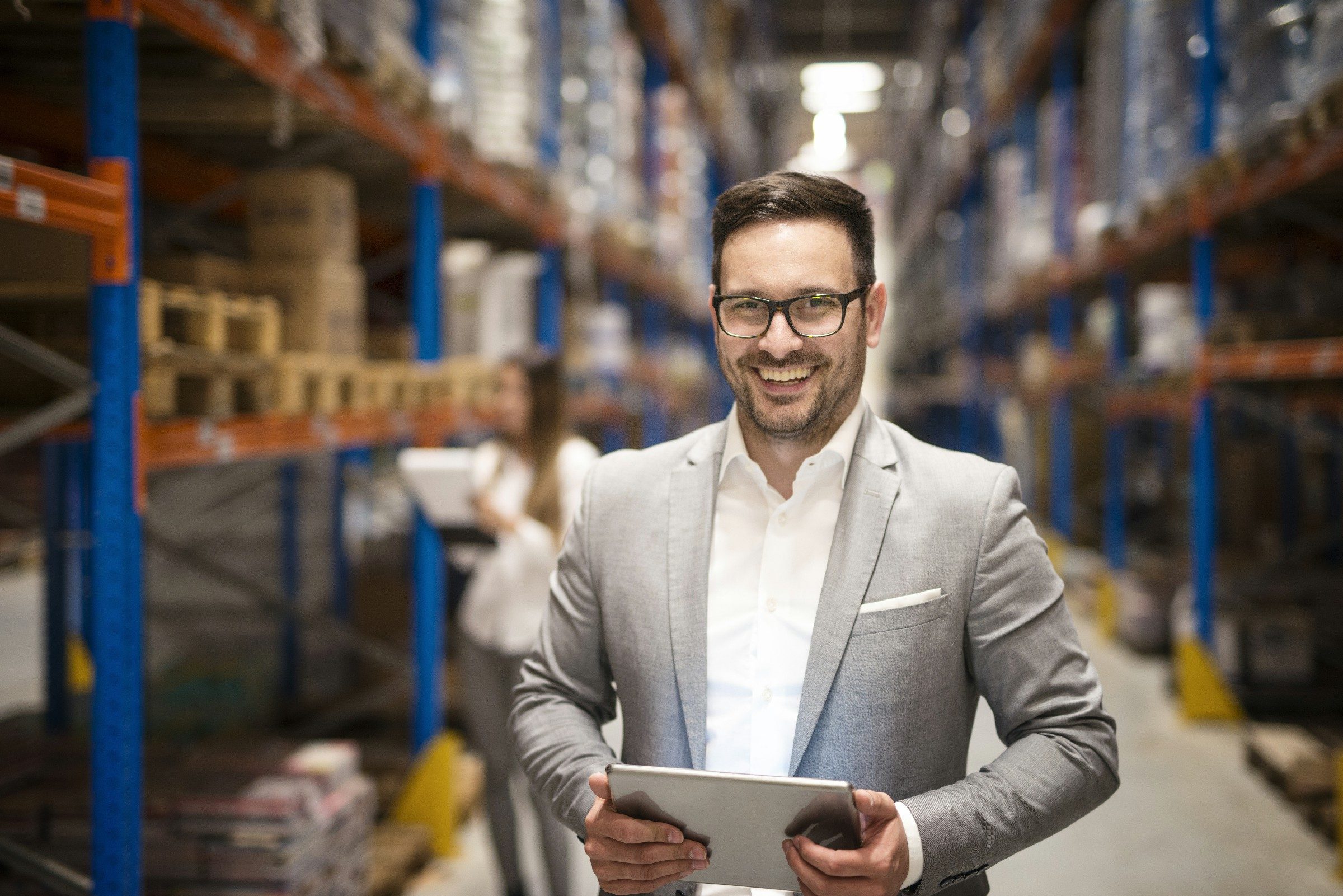 Portrait of successful middle aged caucasian manager businessman holding tablet computer in large warehouse organizing distribution.